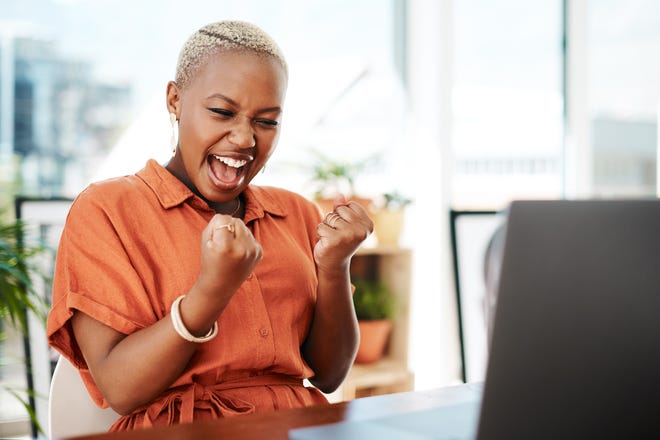 Person celebrating victory while looking at computer.