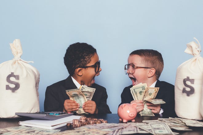 Two children are holding a lot of money and seem completely surprised by their sudden wealth.